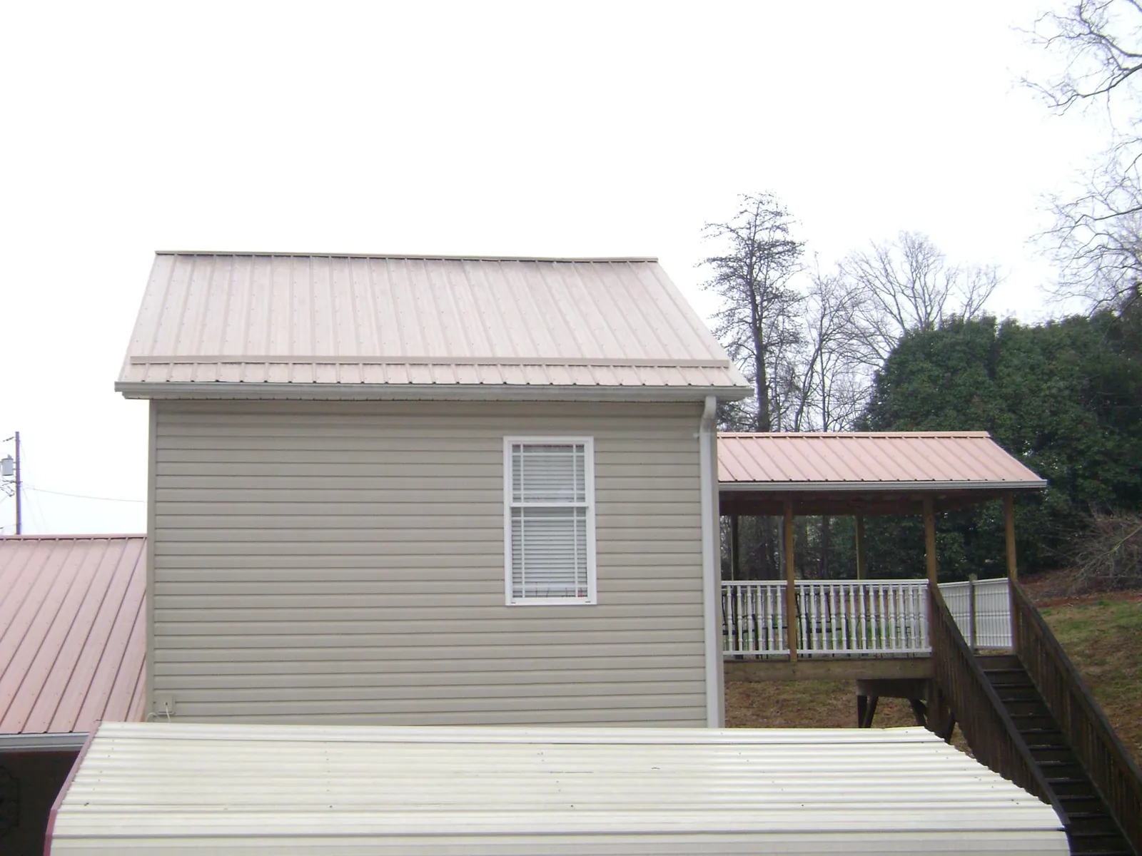 Tan metal roofs on a two story addition and attached porch, from a Roof Replacement job in Powell